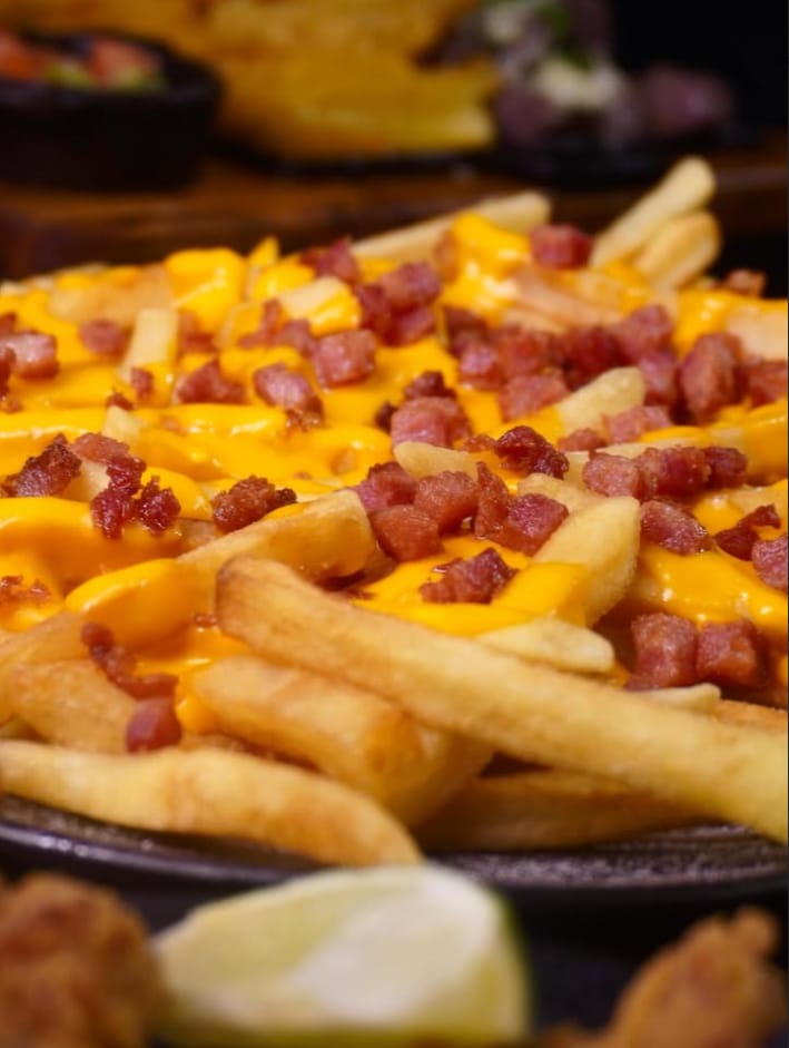 Batata frita coberta com cheddar e bacon em tiras