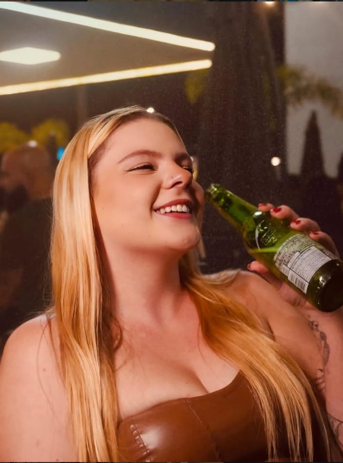 Cliente sorrindo com a long neck na mão durante a noite no Santo Grau